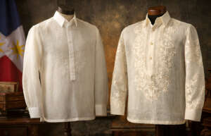 Two formal Barong Tagalog shirts made of translucent piña fabric with intricate embroidery on mannequins, set against a rustic background with a Philippine flag.