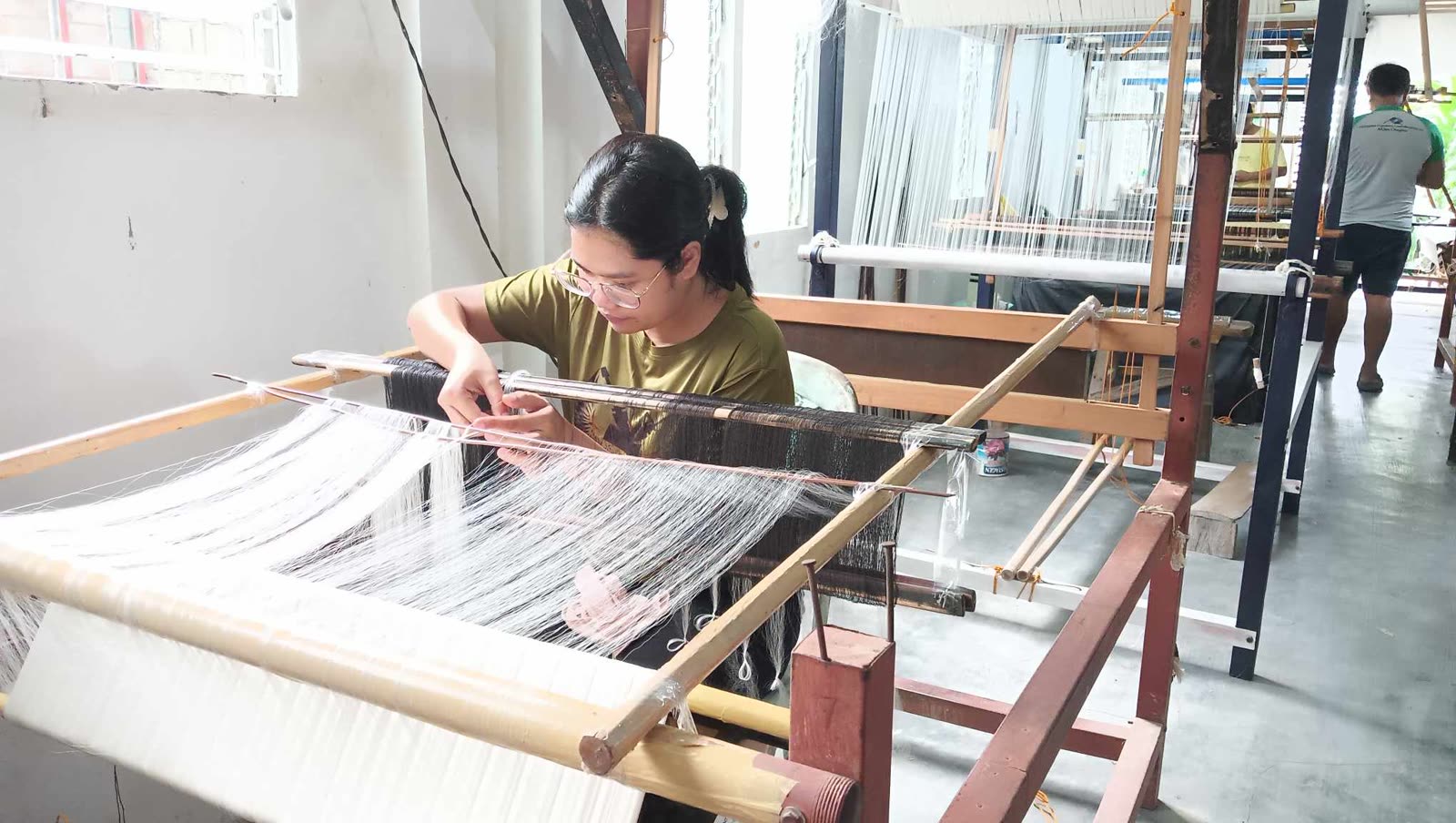 Weaver working sheer barong cloth on a wooden handloom