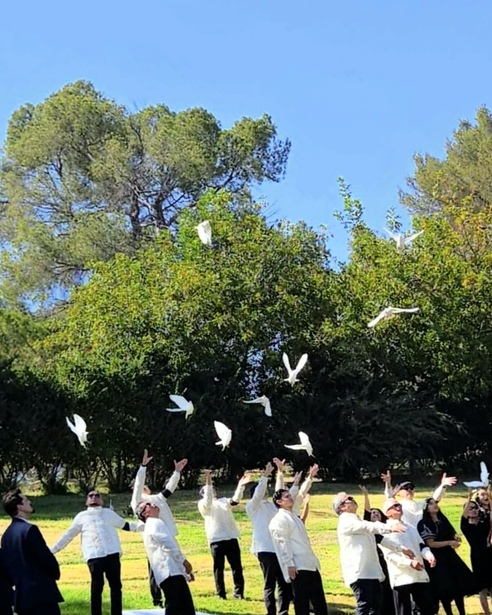 Family in white barong releasing doves at a graveside farewell